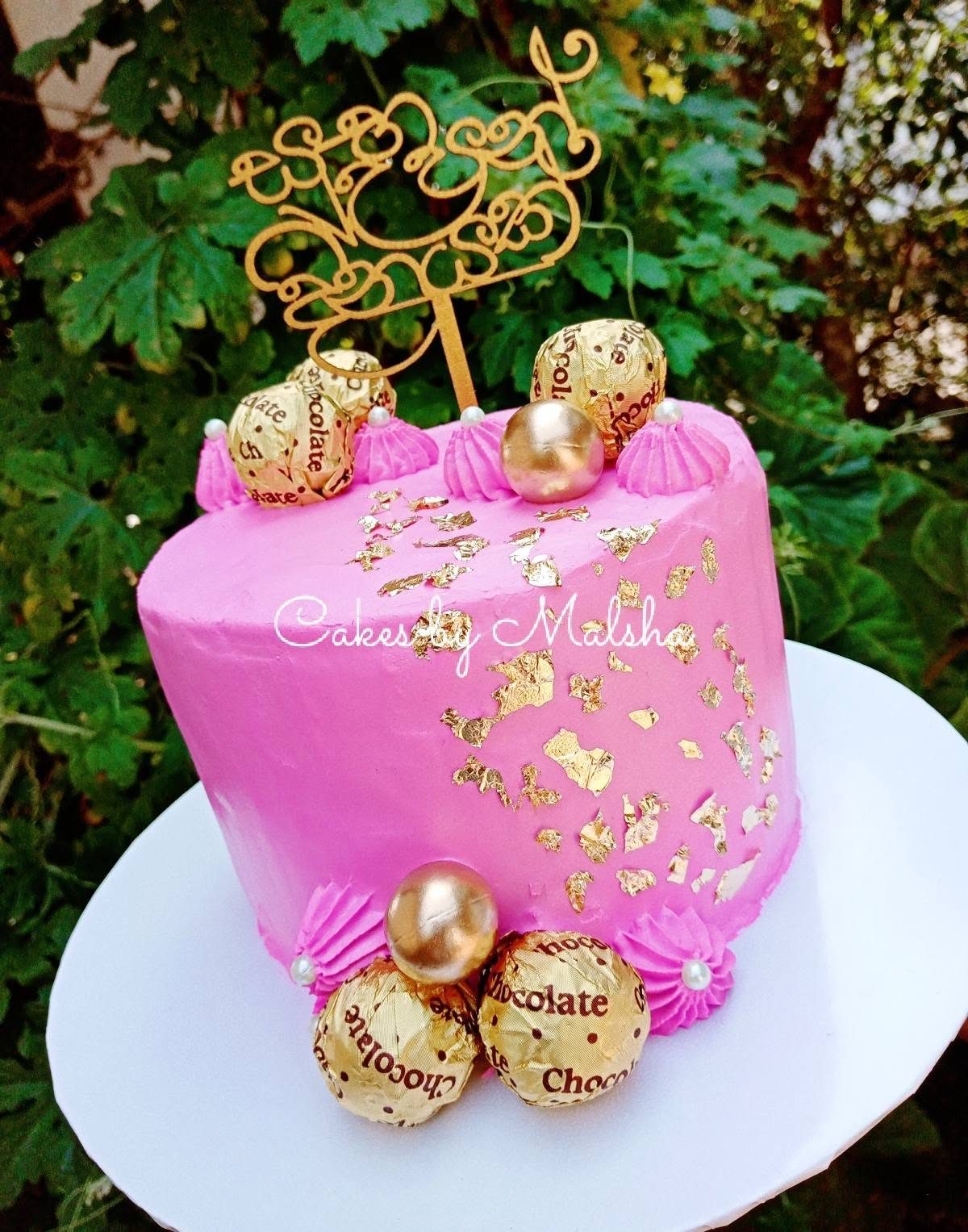 Pink and gold birthday cake with chocolates