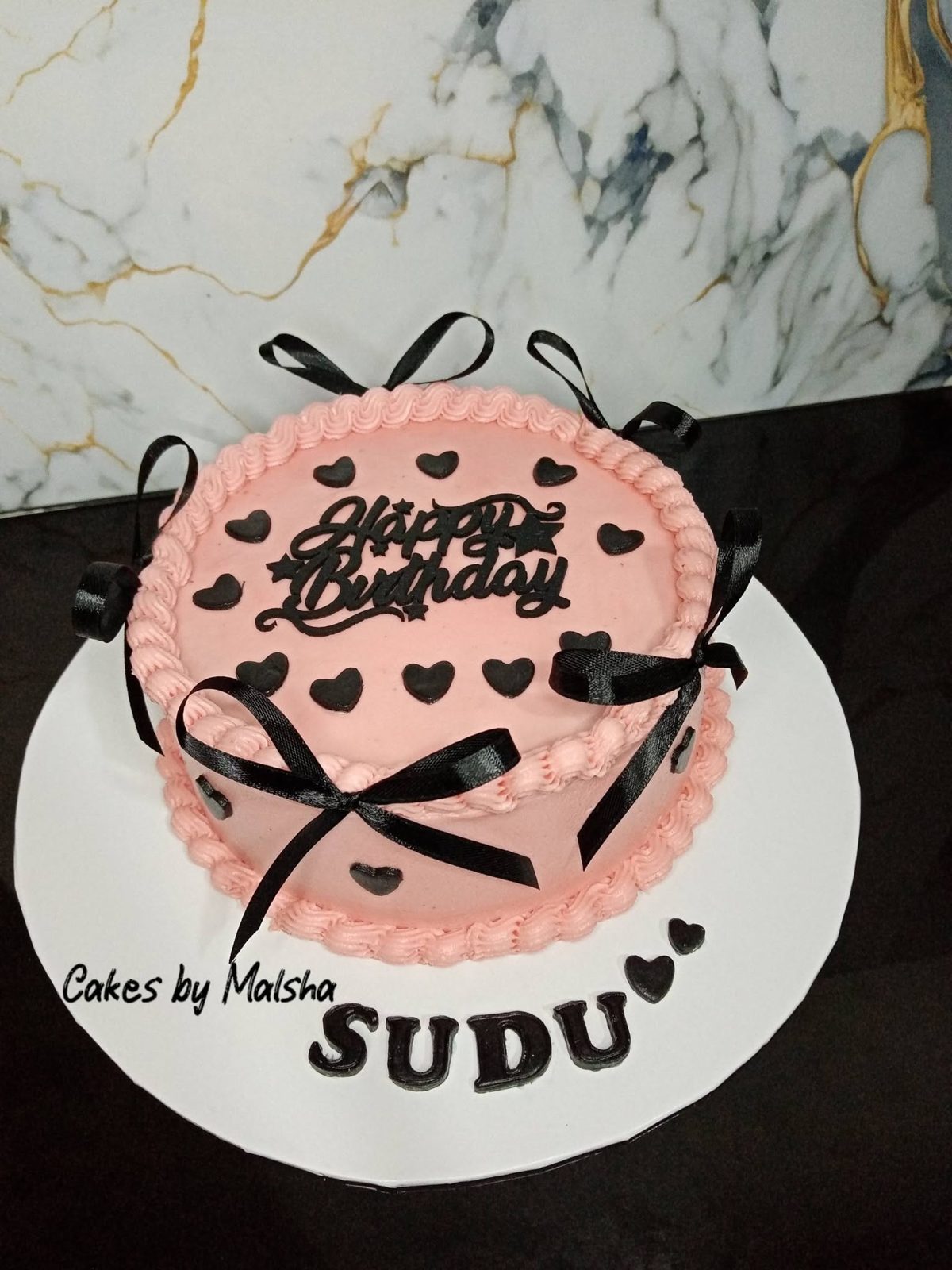 Pink heart birthday cake with a black bow
